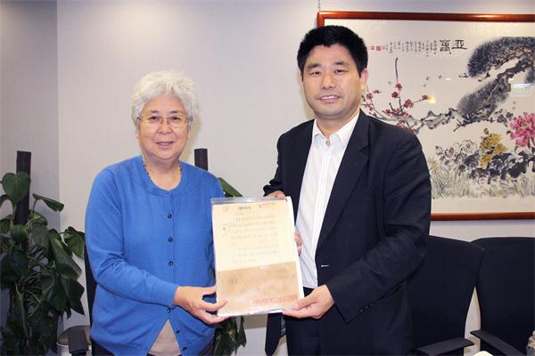 杨勇社长（右）向陈洪原社长展示她当年经手的杂志社宝贵历史资料。